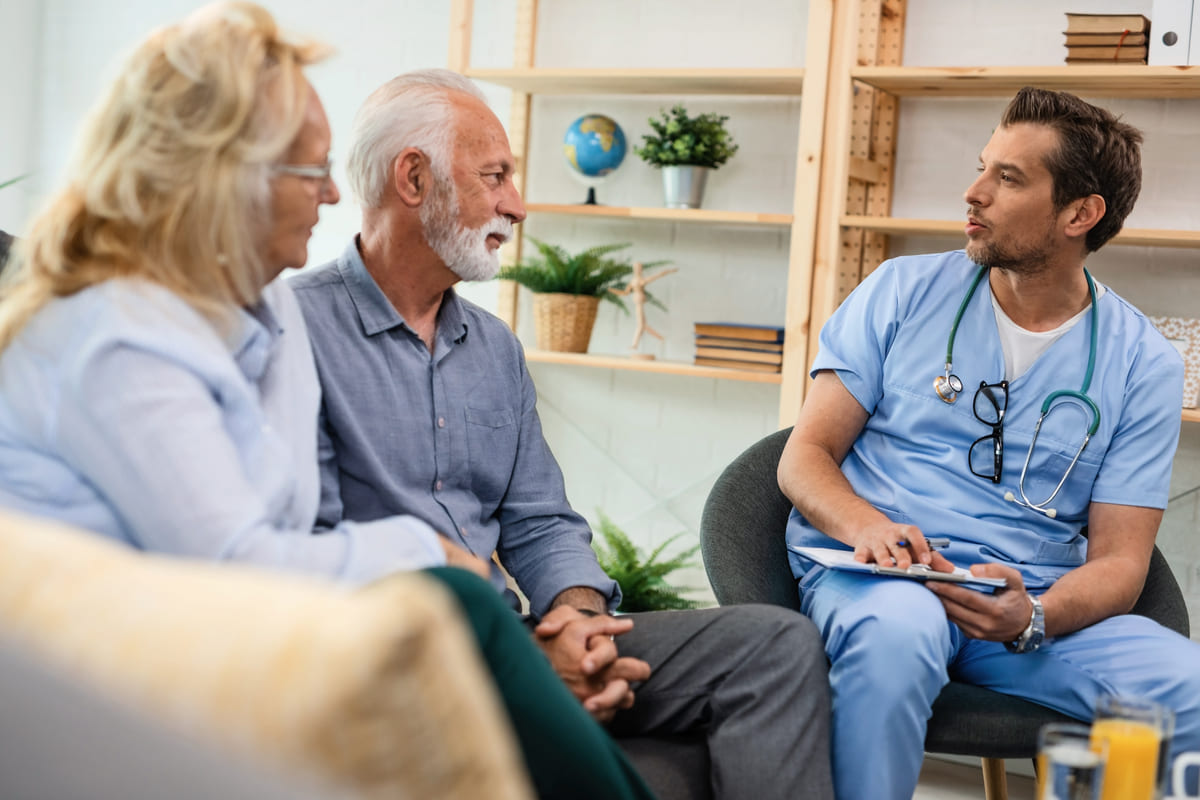 Healthcare Worker Talking With Senior Couple While Being Home Visit